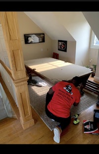 a man installing a bed in a room with stairs