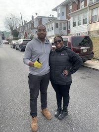 two people standing on a street in front of houses