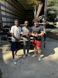 three men standing in front of a moving truck