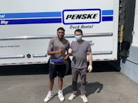 two men standing in front of a truck with masks on